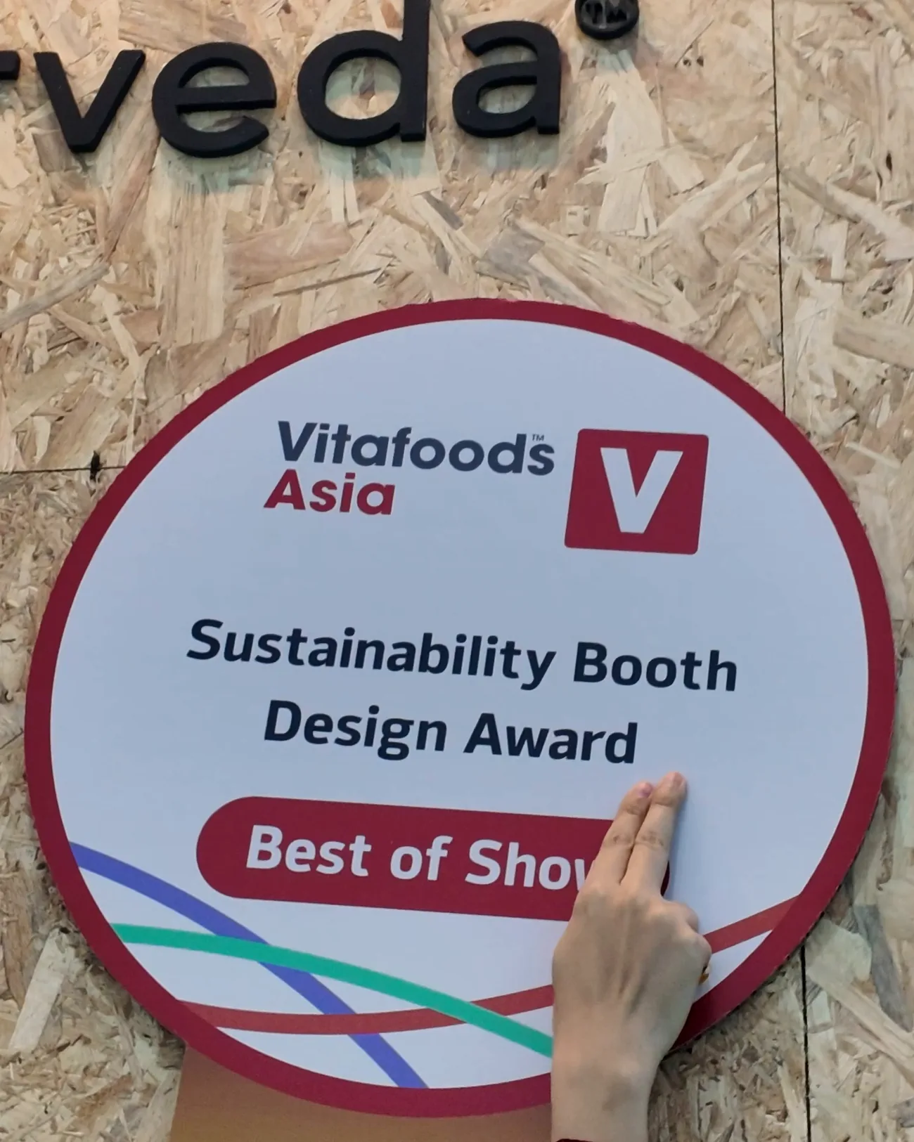 The Vitafoods Asia Best of Show plaque for the Sustainability Booth Design Award, being pinned to the Quantum Ayurveda arch of the booth