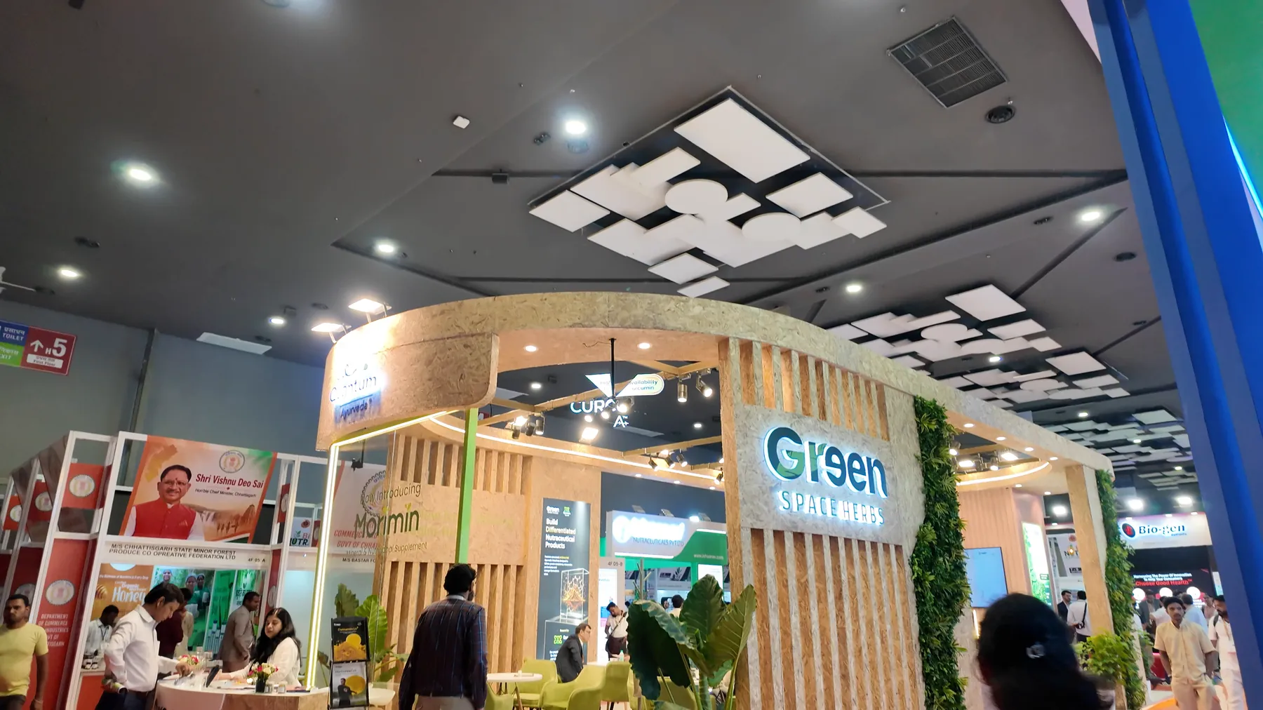 The curved wooden Greenspace Herbs booth at Bharat Nutraverse 2026, the lit sign on its corner