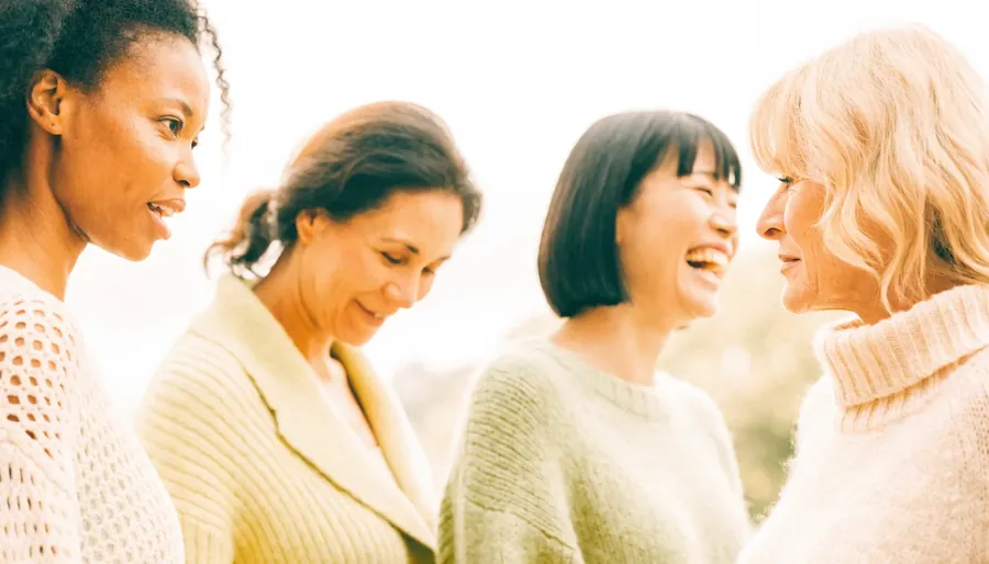 Four friends of different ages laughing together outdoors