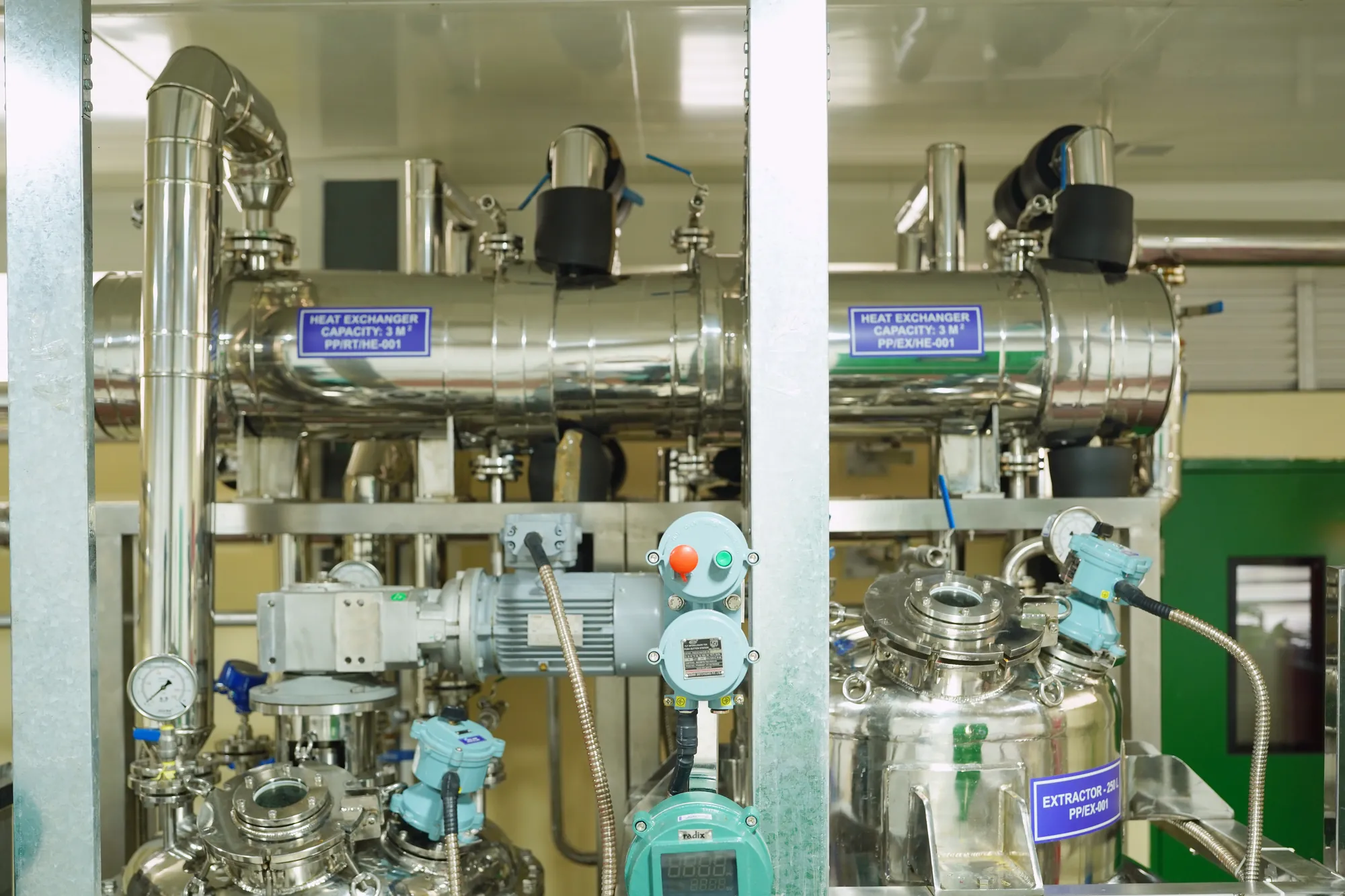 Two stainless heat exchangers mounted above the pilot plant reactors, seen straight on