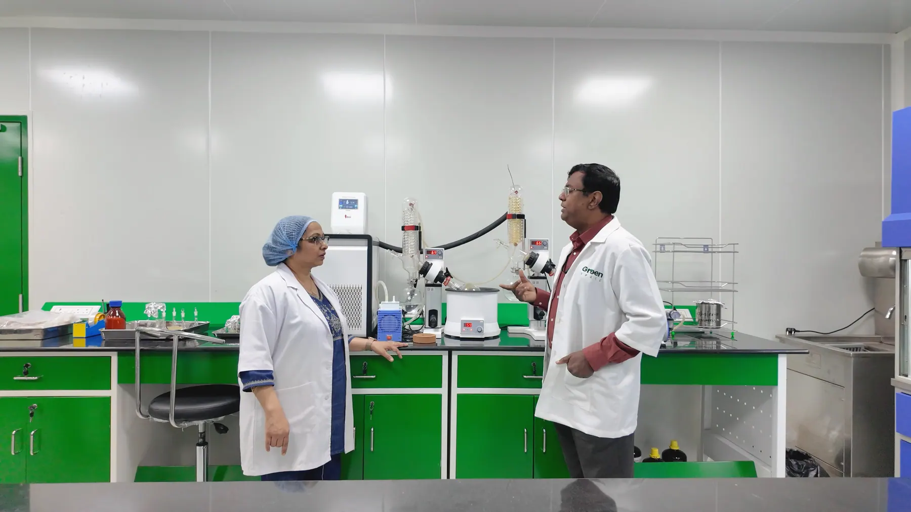 Two Vignanaveda scientists talking at the formulation bench, rotary evaporators between them