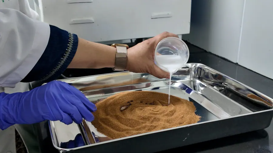 Solvent poured over powdered herb in a steel tray